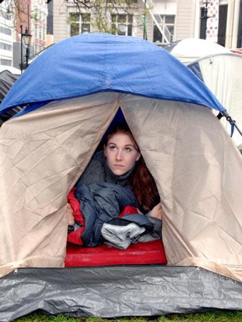 Niamh O'Flynn, part of the "Occupy Dunedin" protest, looks out at the rain from her tent...