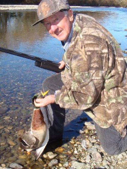 Norm Elliott, of rural Victoria, Australia, kneels by the Mataura River with one of the ducks he...