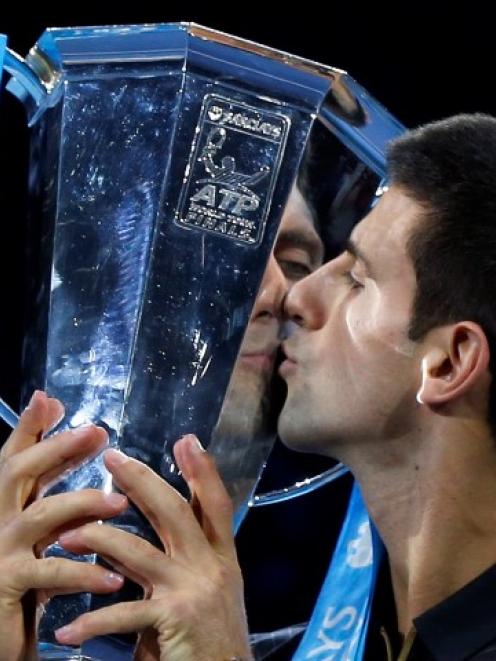 Novak Djokovic kisses the trophy after Roger Federer forfeited due to injury in the men's singles...