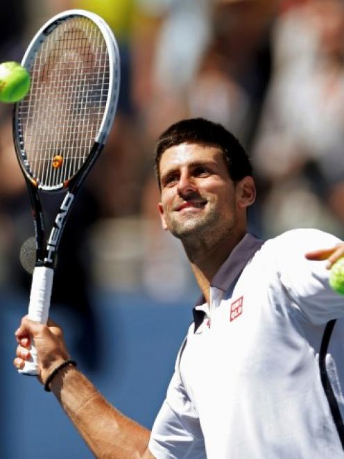 Novak Djokovic of Serbia hits balls to fans after defeating David Ferrer of Spain in their men's...