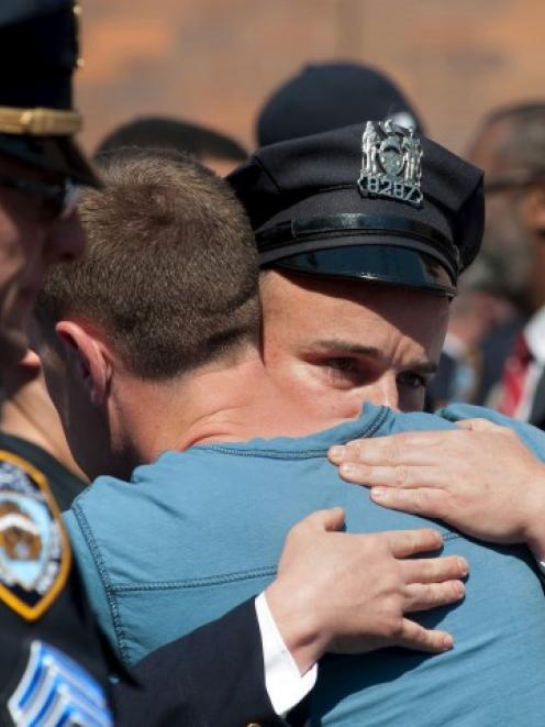 NYPD officers embrace after the body of Brian Moore leaves in an ambulance from Jamaica Hospital...