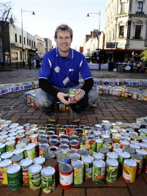 Octacan appeal volunteer Brett Chisholm holds one of the thousands of cans of food donated...