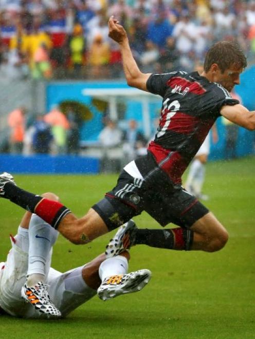 Omar Gonzalez of the US (L) tackles Germany's Thomas Mueller. REUTERS/Tony Gentile