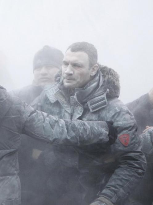 Opposition leader Vitaly Klitschko (C) reacts after he was sprayed with a powder fire...