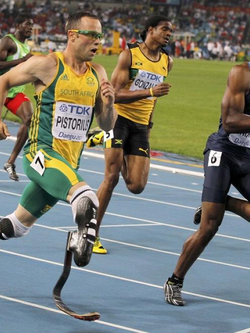 Oscar Pistorius of South Africa (L) runs next to Greg Nixon of the US (R) and Jermaine Gonzales...