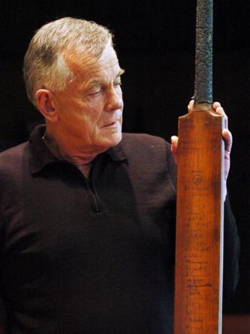 Otago Cricket Association chief executive Ross Dykes examines the 82-year-old souvenir bat signed...
