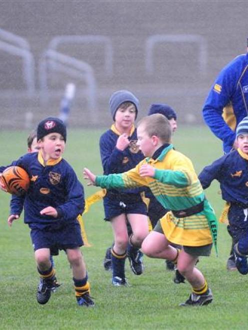 Otago cricket captain Craig Cumming helps control the under-7 rippa rugby game between the...