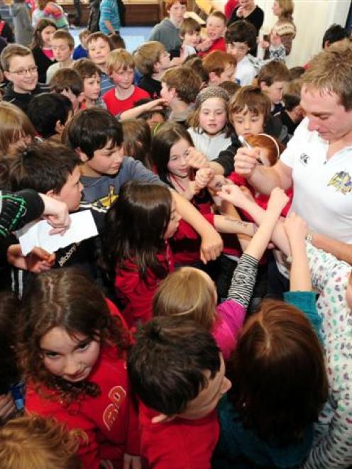 Otago fast bowler James McMillan is mobbed by pupils from years 3 to 6 at Kaikorai Primary School...