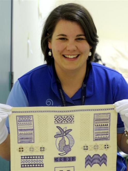 Otago Museum marketing officer Kimberley Smith holds an embroidery sampler made by Ngaere...