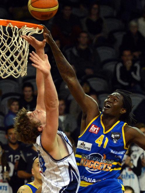 Otago Nuggets centre Warren Carter scores a basket despite the attentions of Giants defender Fin...