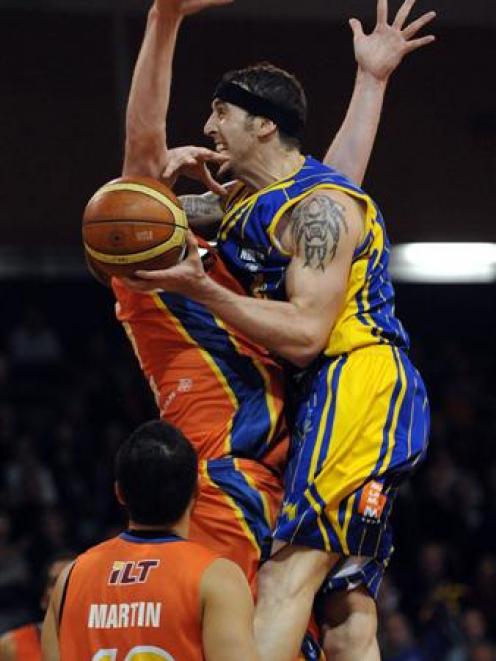 Otago Nuggets forward Tyler Amaya crashes into Southland Sharks defender Gareth Dawson (obscured)...