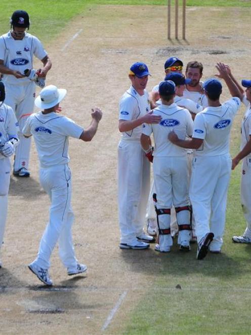 Otago seamer Warren McSkimming is mobbed by his team-mates after dismissing Chris Martin to...