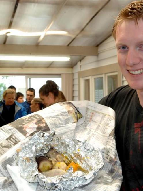 Otago University psychology student John Mighell, of Seattle, unwraps his first hangi at the...