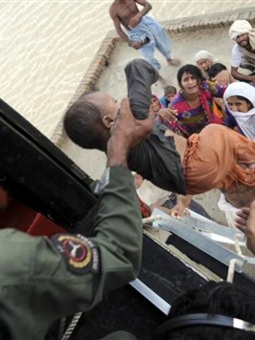 Pakistani army soldiers in a helicopter rescue families stranded by flood water in Sanawan near...