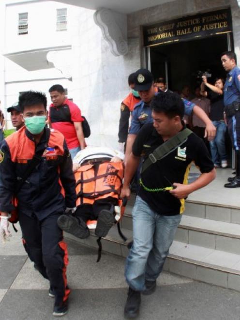 Paramedics and police carry on a stretcher the body of John Pope outside a courtroom in Cebu city...