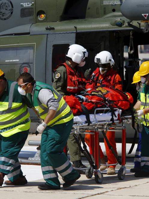 Paramedics wheel an ill migrant on a stretcher away from an Italian military AB212 II helicopter...