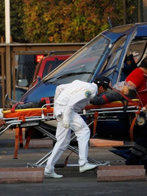 Paramedics wheel an injured person to a helicopter at the parking lot of the state-run oil...