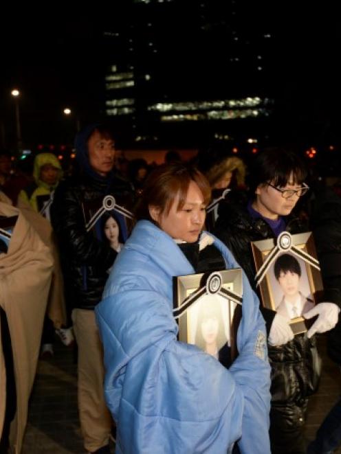 Parents holding portraits of their children, who died on sunken passenger ship Sewol, march...