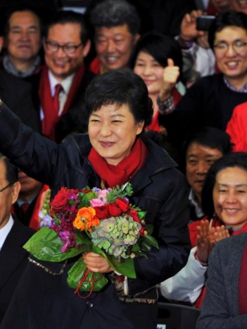 Park Geun-Hye waves as she holds a bouquet of flowers after arriving at the headquarters of the...