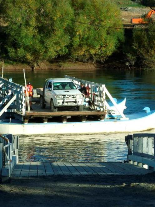 Part-time punt operator Neil Sowry (left) takes Gary Stirling and his ute across the Clutha River...