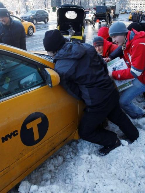 Passersby help push a taxi out of a snow drift in New York after a blizzard pummelled the...