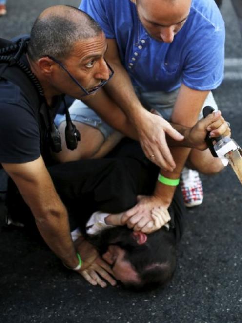 People disarm a man after he allegedly stabbed and injured six participants at an annual gay...