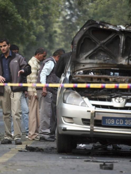 People examine a damaged Israeli embassy car after an explosion in New Delhi. REUTERS/Parivartan...