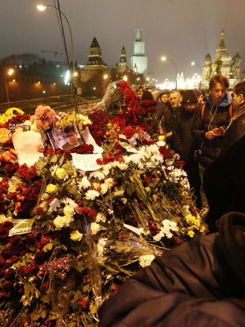 People gather at the site where Boris Nemtsov was recently murdered, with St. Basil's Cathedral...