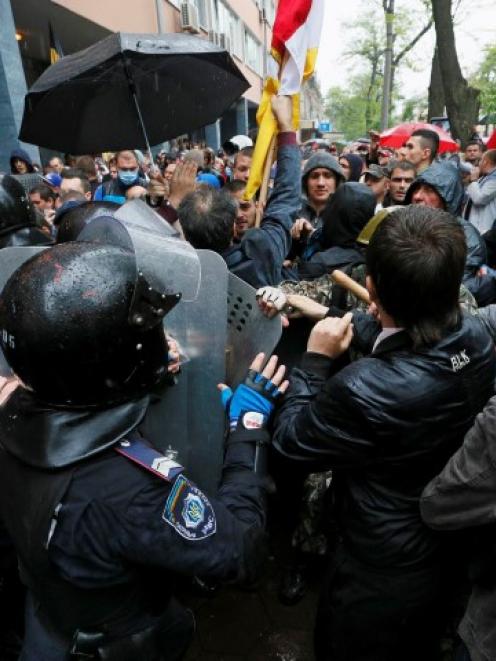People gather in front of Ukrainian Interior Ministry security forces members who form a cordon...