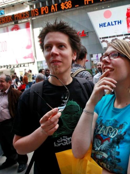 People gather outside the NASDAQ Marketsite waiting to see Facebook's share prices posted inside...