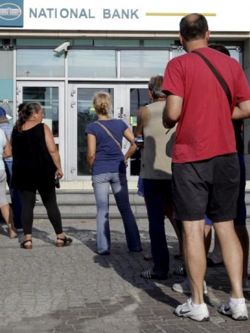 People line up to withdraw cash from an ATM at a bank on the island of Crete. REUTERS/Stefanos...