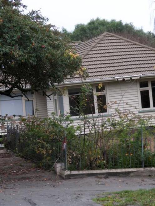 People look at a home in the red zone, in Avonside. Photo by NZPA.