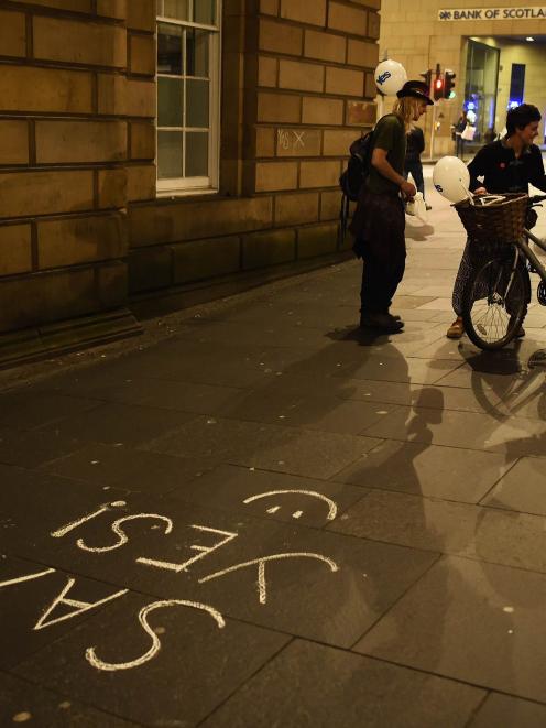 People pass some 'Yes' graffiti on the Royal Mile in Edinburgh, Scotland September 16, 2014. The...