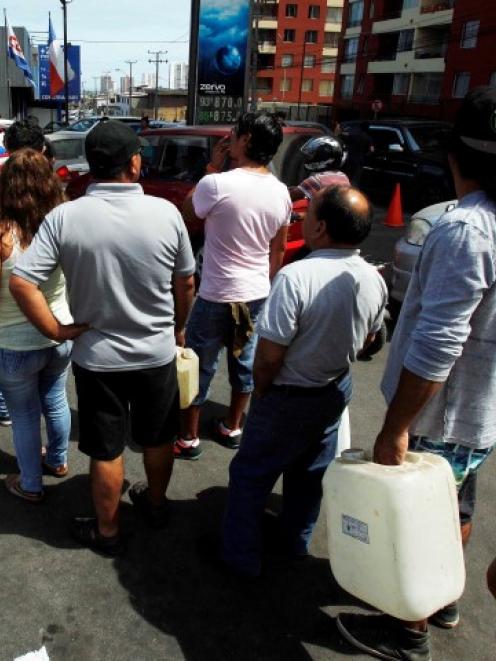 People stand in line to buy fuel in the northern port of Iquique after the earthquake. REUTERS...