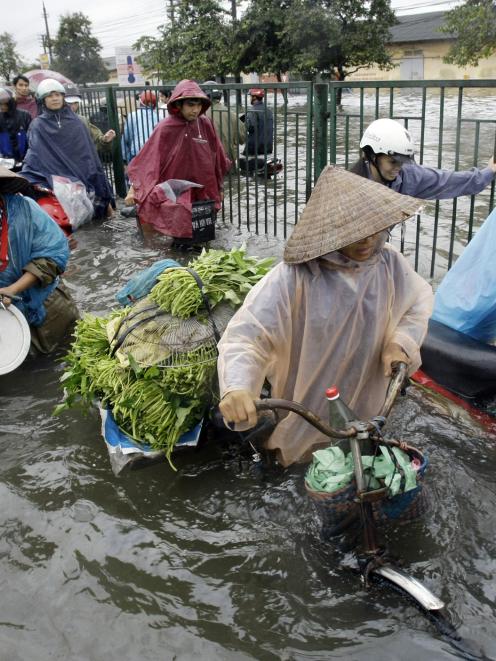 People struggle to walk through a flooded street in Hanoi, Vietnam. Photo by AP.
