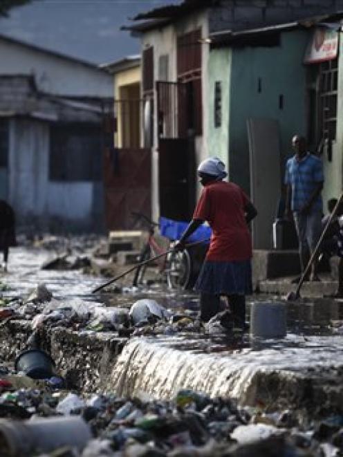 People sweep the garbage that was brought down by heavy rains overnight in the Cite Soleil...