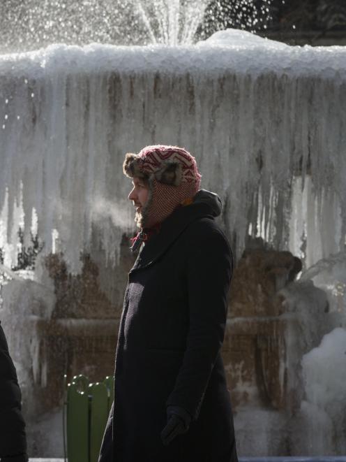 People walk past an ice covered Josephine Shaw Lowell Memorial Fountain, in frigid temperatures...