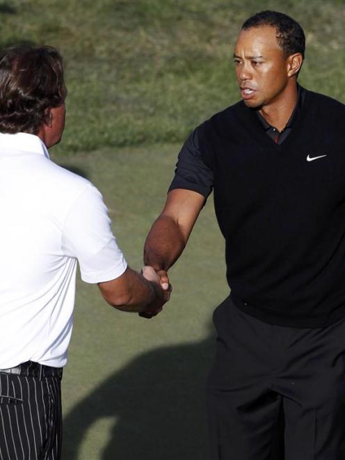 Phil Mickelson and Tiger Woods shake hands on the 18th green during the second round of the 2012...