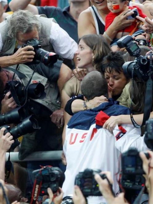Photographers surround Michael and Debbie Phelps, centre, and his sister Whitney Flickinger,...