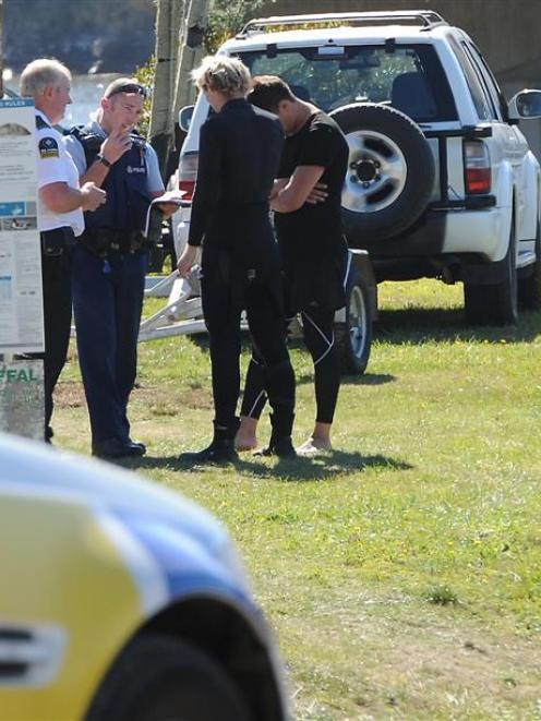 Police and ambulance staff speak to a group of men at Taieri Mouth after their boat flipped when...