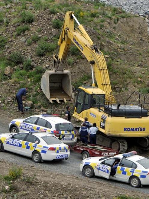 Police and army explosives experts take cover before the gelignite is blown up.