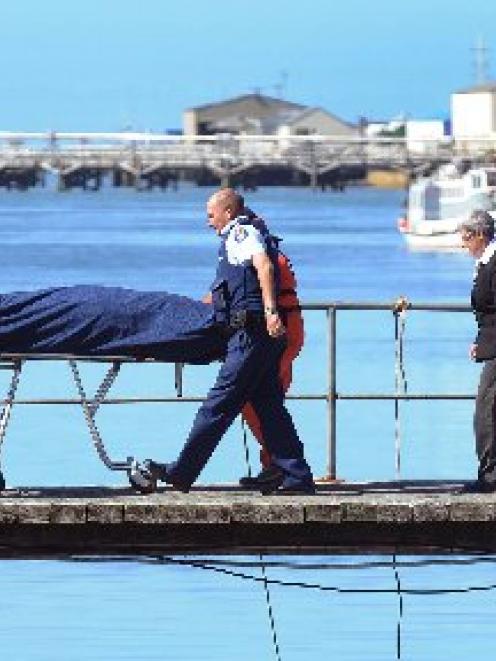 Police and Coastguard personnel carry the body of a man back to shore in Bluff yesterday. Photo...