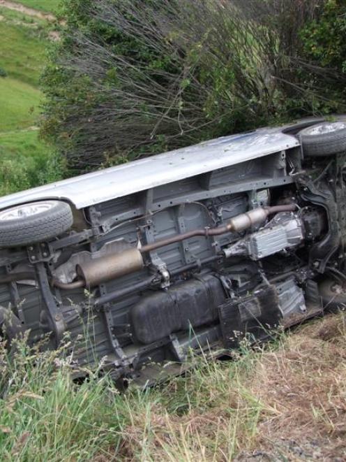 Police Constable Darren Cox, of Balclutha, surveys a damaged vehicle that rolled down a steep...