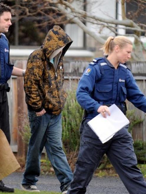 Police escort an arrested man from a Mosgiel house during a police drugs operation yesterday...