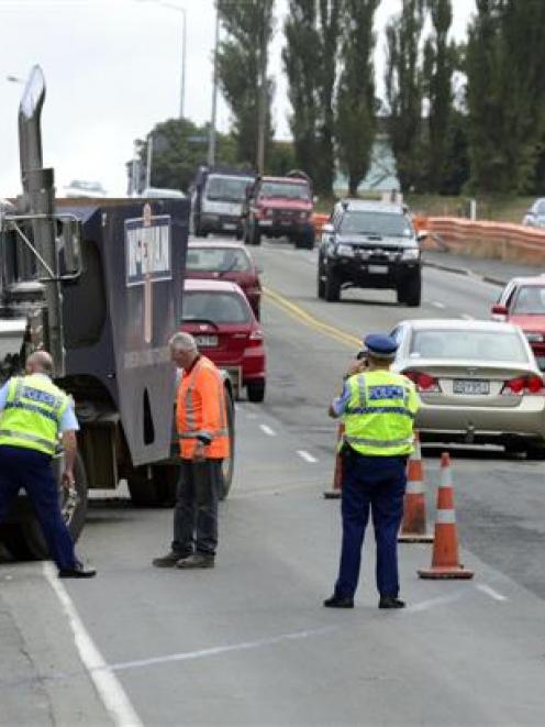 Police inspect a commercial truck after it rolled into a retaining wall beside the south-bound...