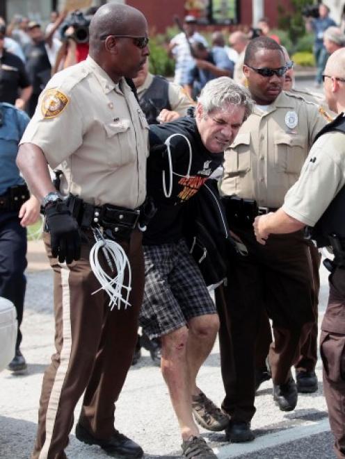 Police officers detain a demonstrator for protesting Michael Brown's murder in Ferguson, Missouri...