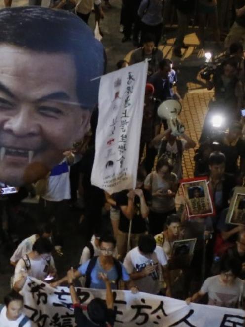 Police officers stand guard as students carry a defaced cutout of Hong Kong Chief Executive Leung...