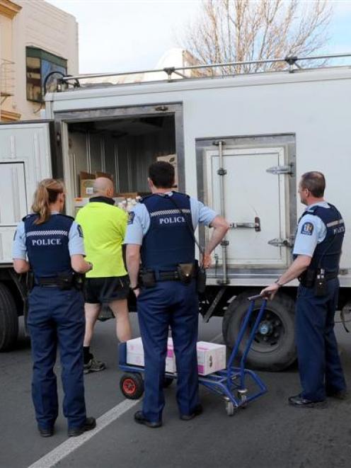 Police officers watch while a delivery driver continues to unload his truck, which he had parked...