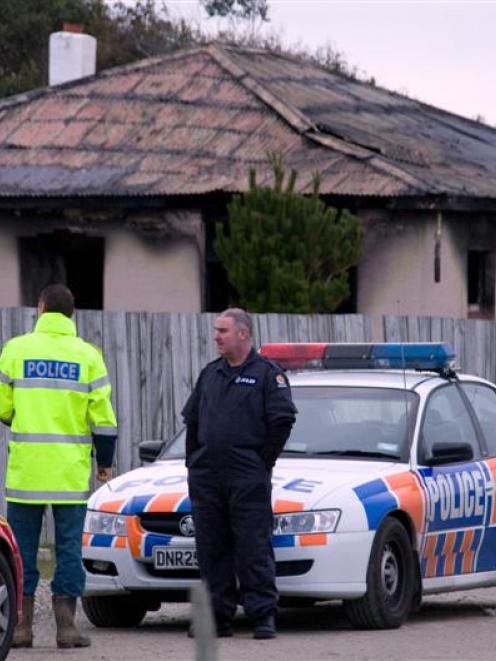 Police stand outside the burnt house yesterday.