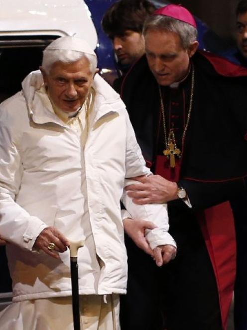 Pope Benedict XVI is assisted as he arrives to attend a meeting with seminarians at the Romano...